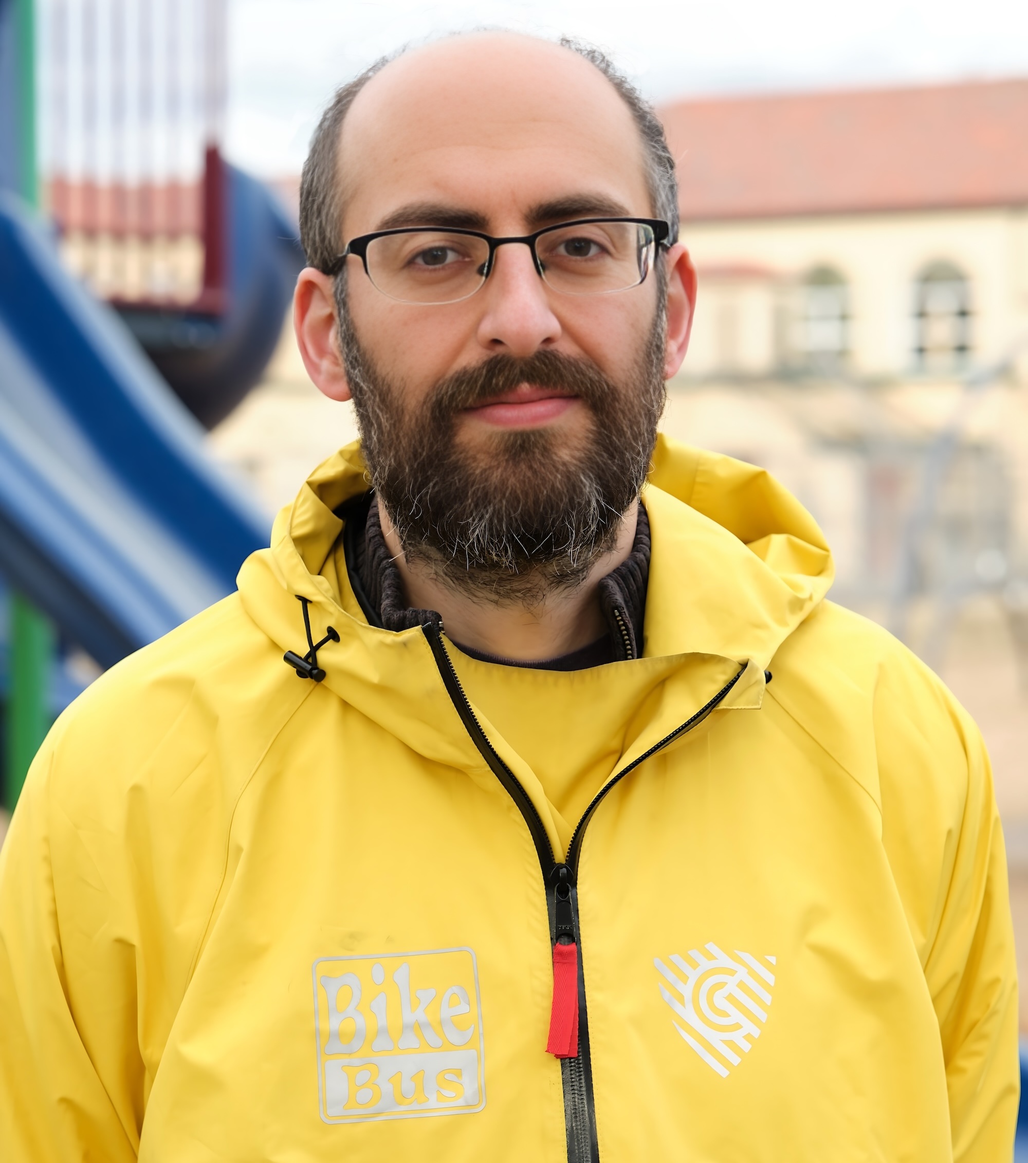 Rob in his yellow Bike Bus jacket in front of a playground.