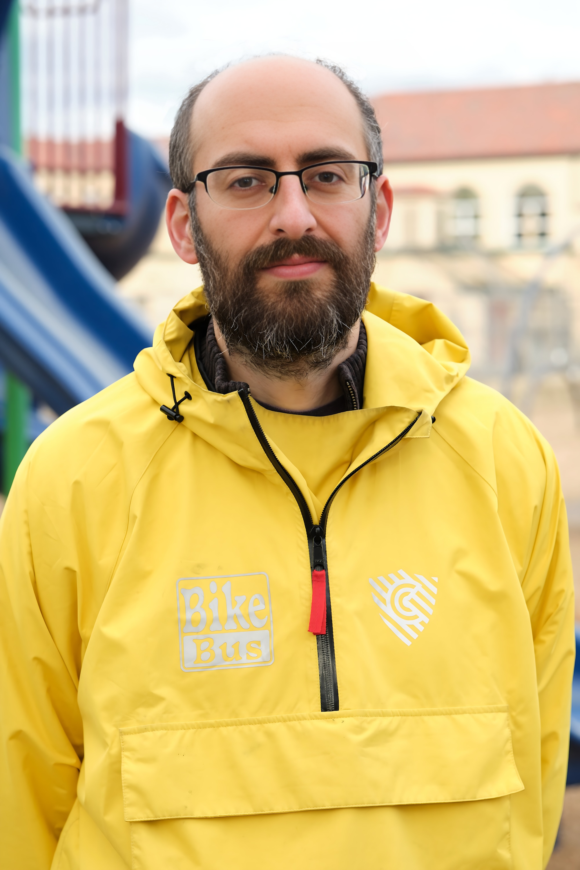 Rob in his yellow Bike Bus jacket in front of a blurred playground.